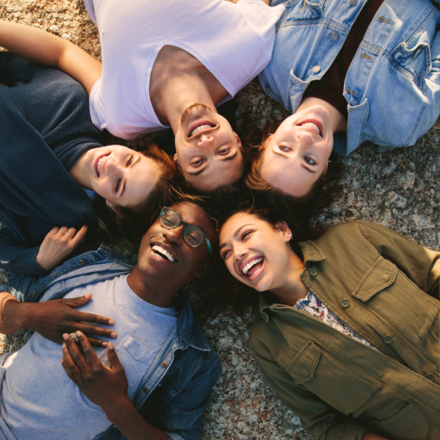 Group of diverse people laying in a circle with heads touching